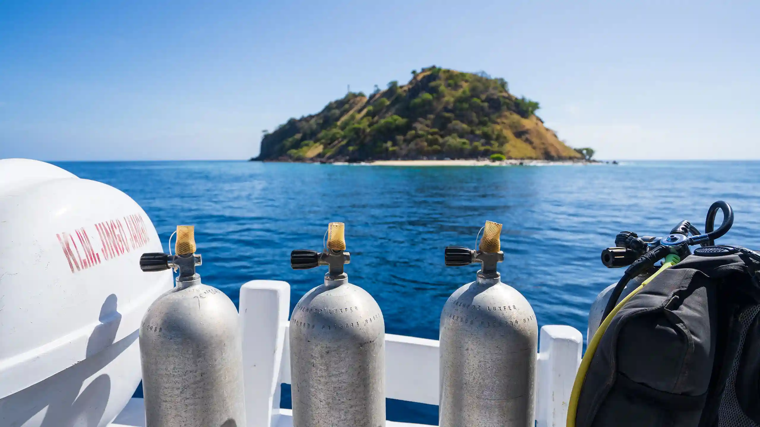 Dive cylinders racked along the rail of a boat deck with an island astern