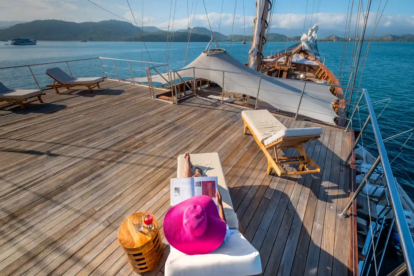 Day bags and sun hats on the timber upper deck of a phinisi under way